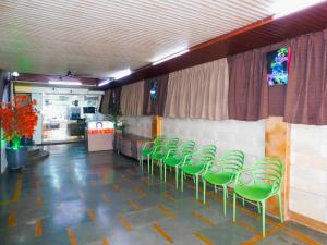 a row of green chairs lined up against a wall at Hotel Nest In in Mumbai