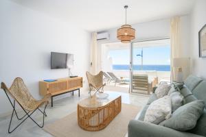 un salon avec un canapé, des chaises et une télévision dans l'établissement Sol Eterno - luxury Aparmtent with direct oceanview and extra services, à Costa Teguise