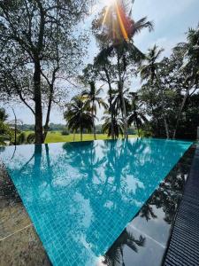 une piscine bleue avec des arbres en arrière-plan dans l'établissement Legato House, à Talpe
