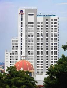 ein hohes weißes Gebäude mit einer roten Kuppel davor in der Unterkunft Horison Ultima Semarang in Jomblang