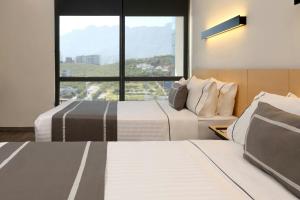 a hotel room with two beds and a window at City Express Plus by Marriott Monterrey Galerías in Monterrey +62 photos