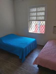 une chambre avec un lit bleu et une fenêtre dans l'établissement Nova Casa Studio Mega - Qto1 c Ar - 3 Vagas Garagem - Esp Térreo Priv - WiFi 300 Megas - Home Office a 200 mts Praia da Pompéia, à Santos