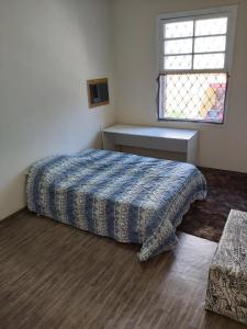 une chambre avec un lit avec une couette bleue et une fenêtre dans l'établissement Nova Casa Studio Mega - Qto1 c Ar - 3 Vagas Garagem - Esp Térreo Priv - WiFi 300 Megas - Home Office a 200 mts Praia da Pompéia, à Santos