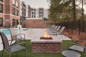 达拉姆Fairfield by Marriott Inn & Suites Durham的一个带椅子和游泳池的庭院内的火坑