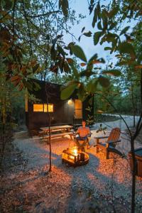a man sitting around a fire in front of a cabin at Postcard Cabins Gilchrist Springs, Outdoor Collection by Marriott Bonvoy in High Springs