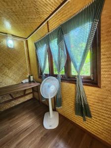 a room with a fan and a window with curtains at Mook Bamboo Bungalows in Koh Mook
