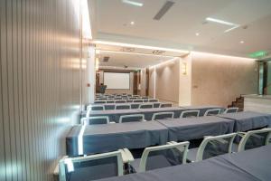 une salle de conférence avec des rangées de chaises et un écran dans l'établissement Tomeet Hotel, à Meizhou