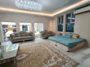 een slaapkamer met een bed en een woonkamer met een kroonluchter bij Luxury Villa Mansion Ajman in Ajman 