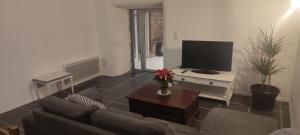 een woonkamer met een bank en een flatscreen-tv bij Gîte L'hôtellerie in Trévron