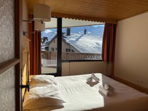 een slaapkamer met een bed en een groot raam bij Résidence Le Portillo in Val Thorens
