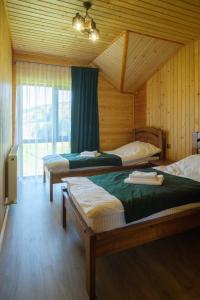 a bedroom with two beds in a wooden cabin at Шепіт Карпат in Yasinya