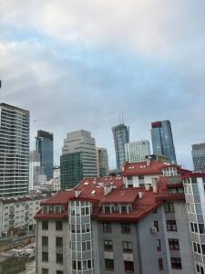 a building with a red roof in front of a city at Zakątek in Warsaw