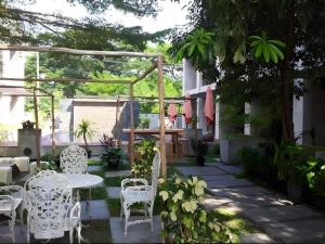 een patio met witte stoelen, een tafel en een pergola bij Klim Hotel in Buriram