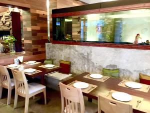 een eetkamer met houten tafels en witte stoelen bij Klim Hotel in Buriram