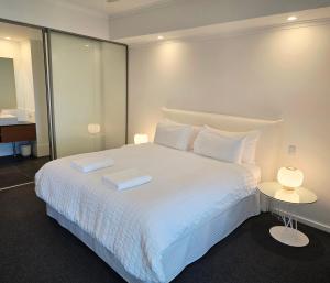 a bedroom with a large white bed with two tables at HAVEN by the Sea in Mandurah