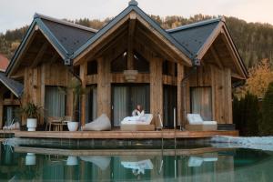 een vrouw zit op de veranda van een huis aan het water bij Hotel Rosenhof Murau in Murau