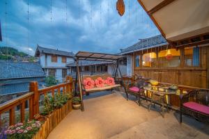 a balcony with a swing and a table and chairs at Travel & Rest Inn in Lijiang