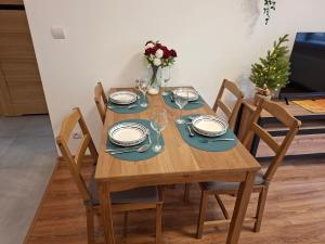 een houten tafel met borden en wijnglazen erop bij Apartament City Dream in Legnica
