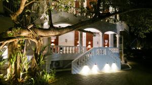 a house with a white fence and a tree at White Coco Luxury Villas, Private Pool, North Goa in Baga