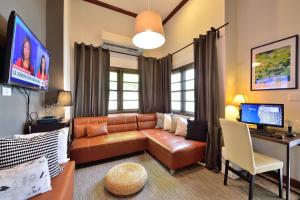 a living room with a brown leather couch and a desk at Lost and Found Bed and Breakfast in Bangkok