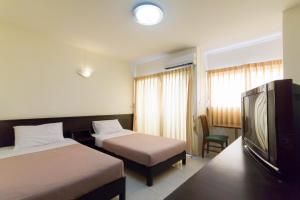 a hotel room with two beds and a flat screen tv at Mont Talay Hotel in Prachuap Khiri Khan