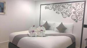 een slaapkamer met een wit bed met 2 bloemen erop bij white house in Phangnga