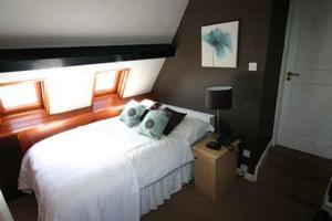 a bedroom with a white bed with blue pillows at Lulus in St Bees