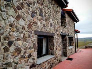 un edificio de piedra con 2 ventanas laterales en La Casona del Silencio, en Canos