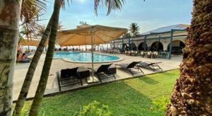 een zwembad met stoelen en een parasol naast een resort bij Lago de Oro in Balibago