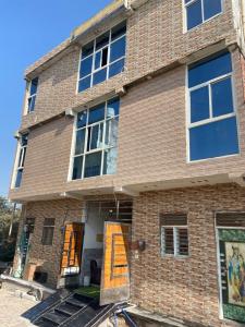 ein Backsteinhaus mit offenen Eingangstüren in der Unterkunft Shri Ladli Ji Guest House in Chhatikara