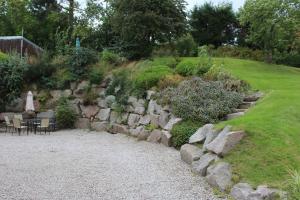 a garden with a stone wall and a table and chairs at Dunmhor Guest House in Kingussie
