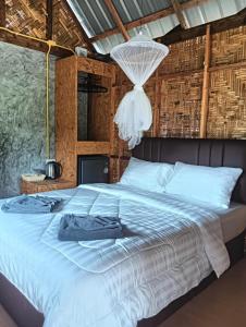 een slaapkamer met een groot wit bed met een kroonluchter bij Bansuan Lanta Maikaew in Koh Lanta