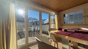a room with a table and chairs and a balcony at Die Talstation in Riezlern