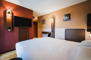 a bedroom with a white bed and a flat screen tv at Hota Hotel Porrentruy in Porrentruy