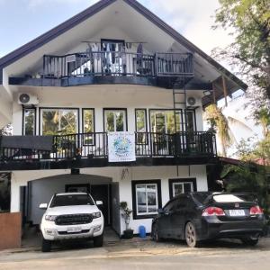 twee auto's geparkeerd voor een huis bij Aljay & Joan's Homestay in Pagudpud