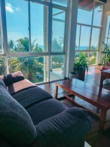 een woonkamer met een bank, een tafel en ramen bij Celestia by Sea Cloud in Talpe