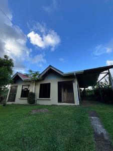 een wit huis met een grasveld ervoor bij Cabaña La Conquista in Sarapiquí