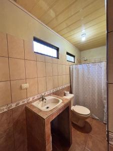 een badkamer met een wastafel en een toilet en een raam bij Cabaña La Conquista in Sarapiquí