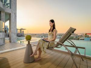 een jonge vrouw zit op een stoel op een balkon bij HuiKe MARITZTLE HOTEL in Ban Bang Toei (1)