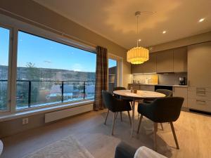 a kitchen with a table and chairs and a large window at Motoppen Trysil Apartments in Trysil