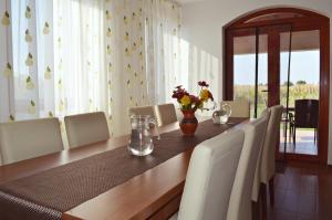 a dining room table with white chairs and a vase of flowers at Pensiunea Ana in Odoreu