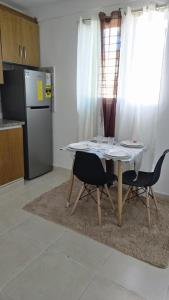 een keuken met een tafel en 2 stoelen en een koelkast bij 4 vecinos in Santiago de los Caballeros