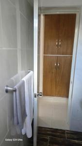 een badkamer met een douche met een witte handdoek en een deur bij 4 vecinos in Santiago de los Caballeros
