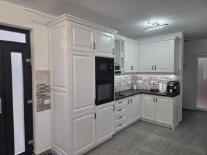 eine weiße Küche mit weißen Schränken und schwarzen Geräten in der Unterkunft Pensiunea Dariana in Bucium-Sat
