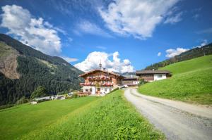 dom na wzgórzu obok polnej drogi w obiekcie Ferienhof Wölflbauer w Saalbach Hinterglemm