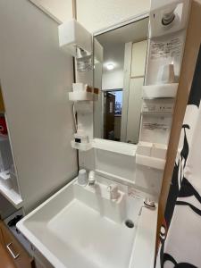 een badkamer met een witte wastafel en een spiegel bij サムライ シティ イン 信夫屋 in Aizuwakamatsu