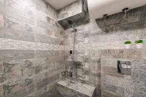 een badkamer met douche met een stenen muur bij Dany's Apartments in Varna