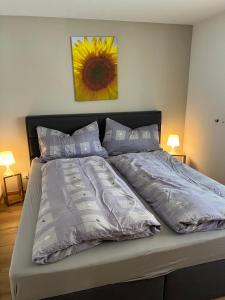 a bed in a bedroom with a sunflower on the wall at Residence Edelweiß in Bellwald in Bellwald