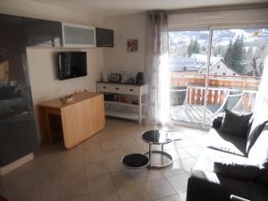 sala de estar con sofá y cocina con balcón en les gentianes, en La Salle-les-Alpes