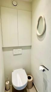 a white bathroom with a toilet and a mirror at Seanest - North Sea Stays in De Haan +27 photos